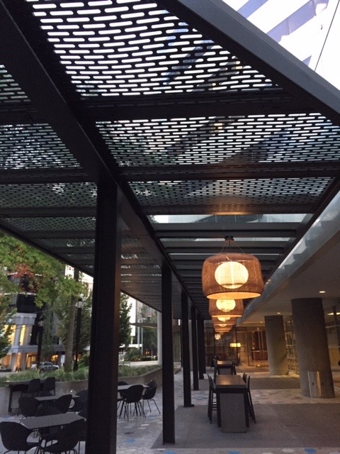 Perforated architectural steel canopy over a plaza